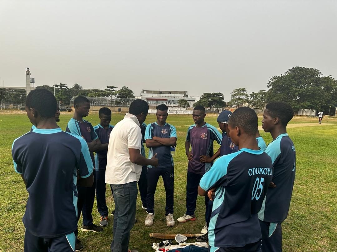 Players gathered in a huddle beside their kit on the boundary